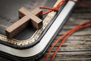 Closeup of simple wooden Christian cross necklace on holy Bible